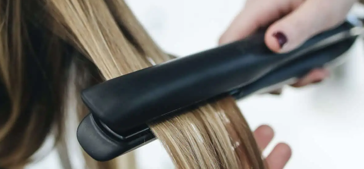 Person ironing a womans hair